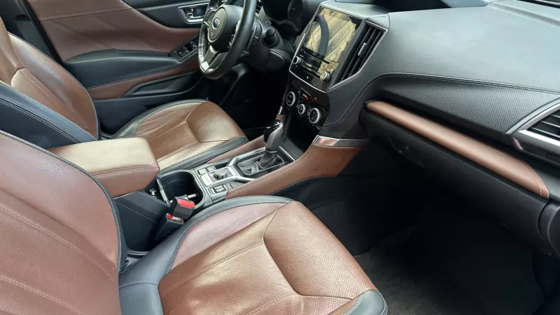 Interior of a modern SUV with brown leather seats, black dashboard, steering wheel, and center touchscreen panel.