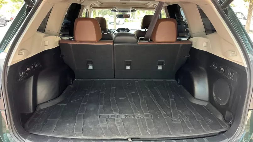 Cargo area of a Subaru SUV with rear seats up and a black rubber cargo mat.